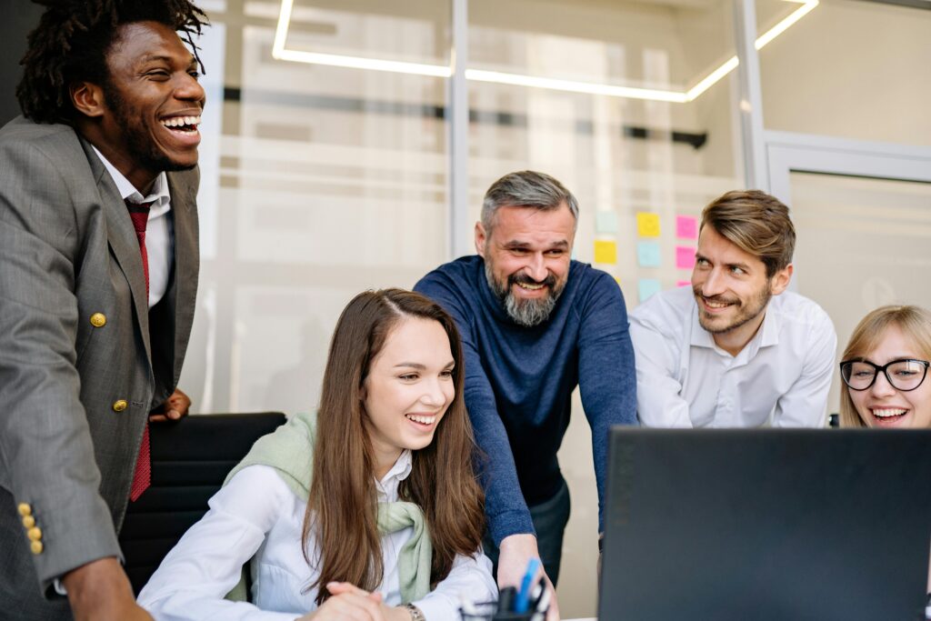 A diverse group of colleagues enthusiastically collaborating on a project in a brightly lit modern office.